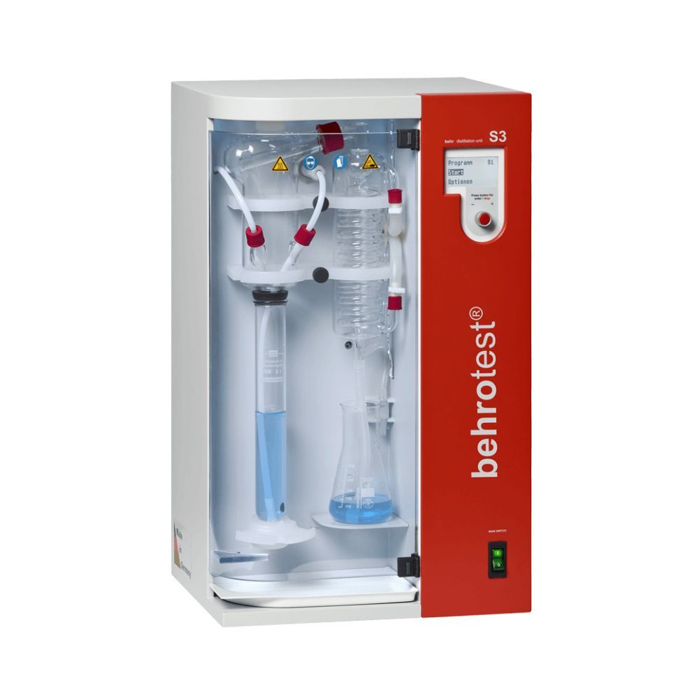Steam distillation unit for nitrogen determination with a glass apparatus, reagent control tubing, and a red front panel with digital controls.