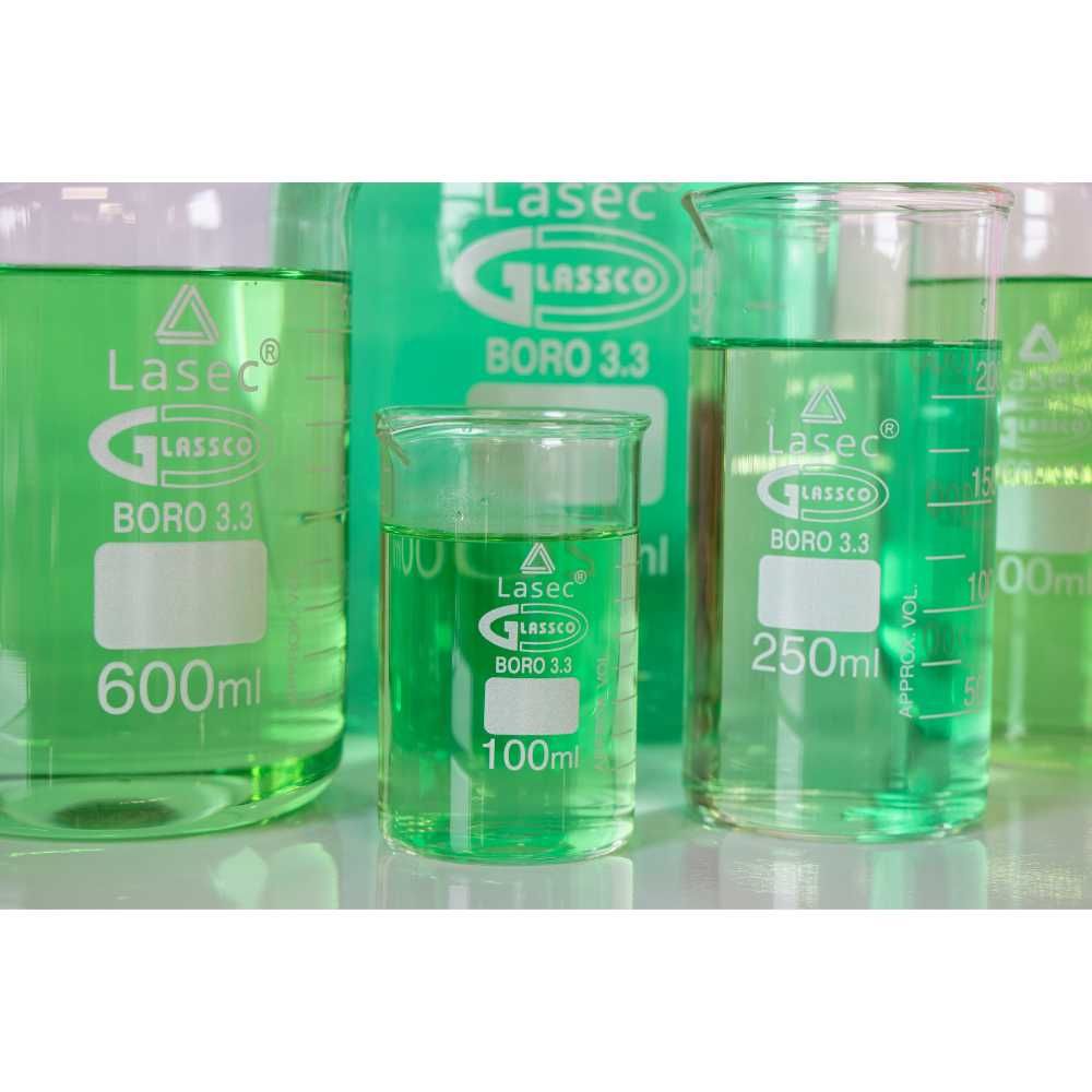 Close-up of borosilicate glass beakers with green liquid, marked with 'Lasec Glassco' branding, showing volume measurements.