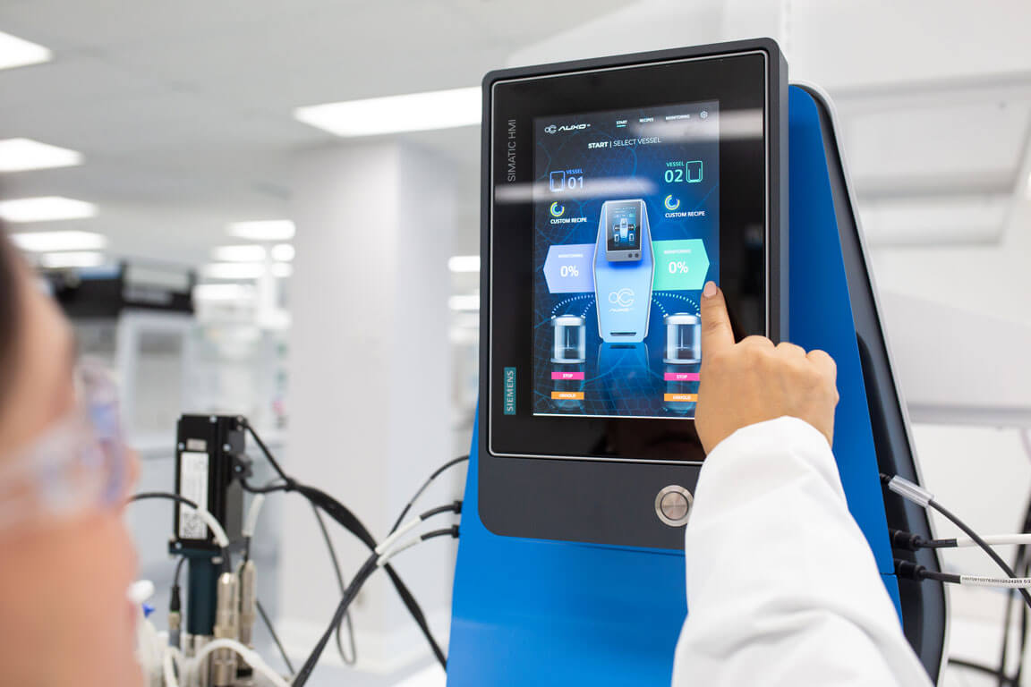 Close-up of AUXO V benchtop bioreactor touchscreen control panel showing vessel monitoring interface.