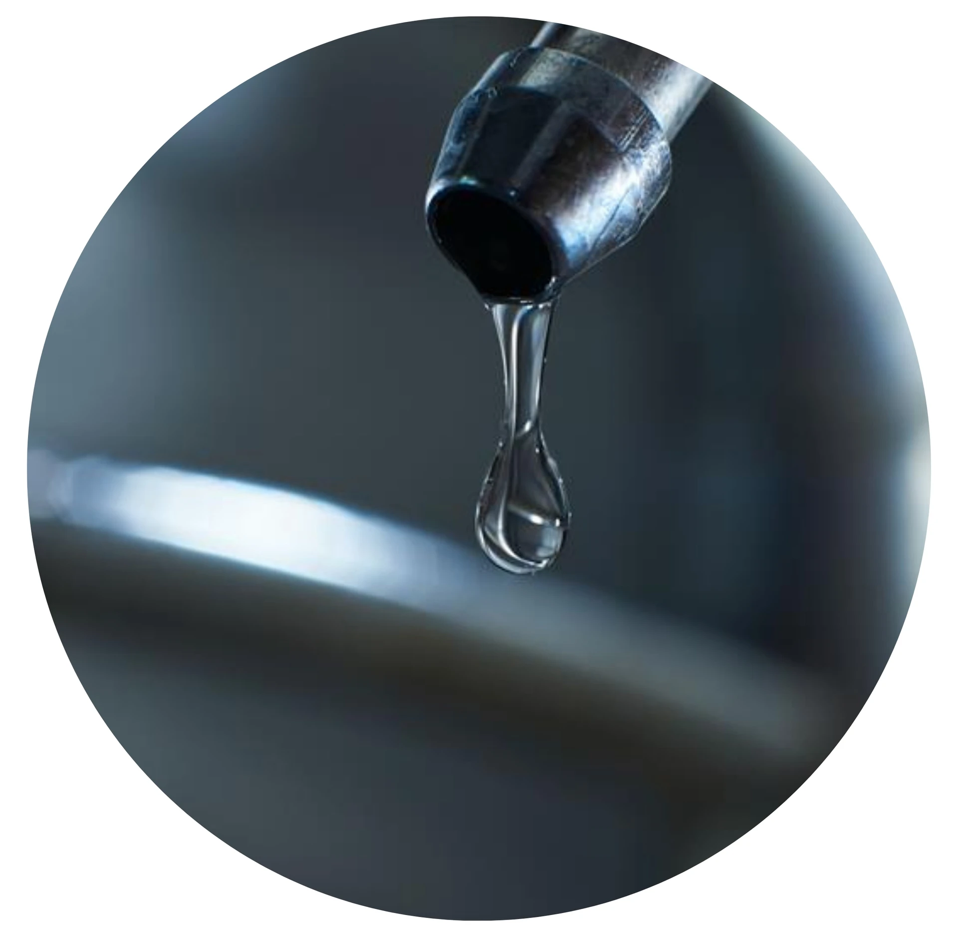 Close-up of a single drop of liquid forming at the end of a metallic nozzle, highlighting precision fluid dispensing or purity in liquid applications.