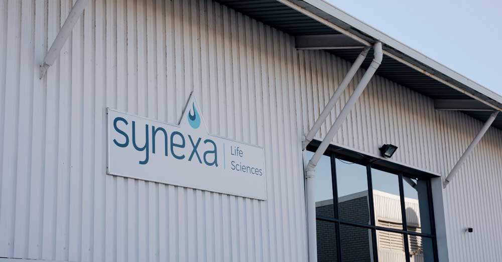 Exterior of the Synexa Life Sciences building with company sign on a white corrugated facade.